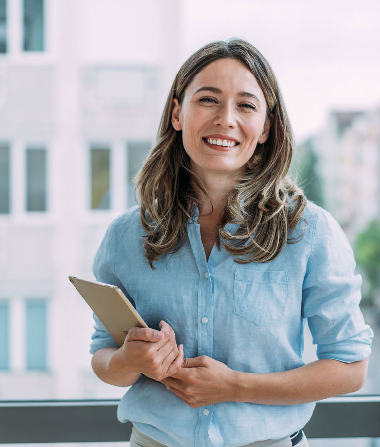 Smiling professional woman holding a tablet, representing modern technology for workforce management and efficient team coordination.