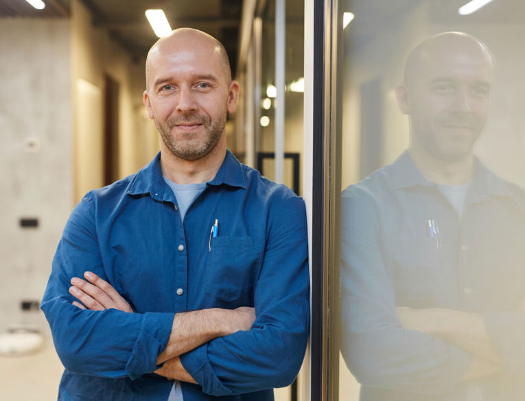 Man in a casual office environment exuding confidence and professionalism, ideal for showcasing career opportunities in workforce management, scheduling, and time tracking
