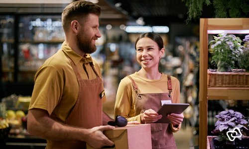Retail employees reviewing summer holiday workforce scheduling, optimising staffing levels, shifts and time tracking in a busy store