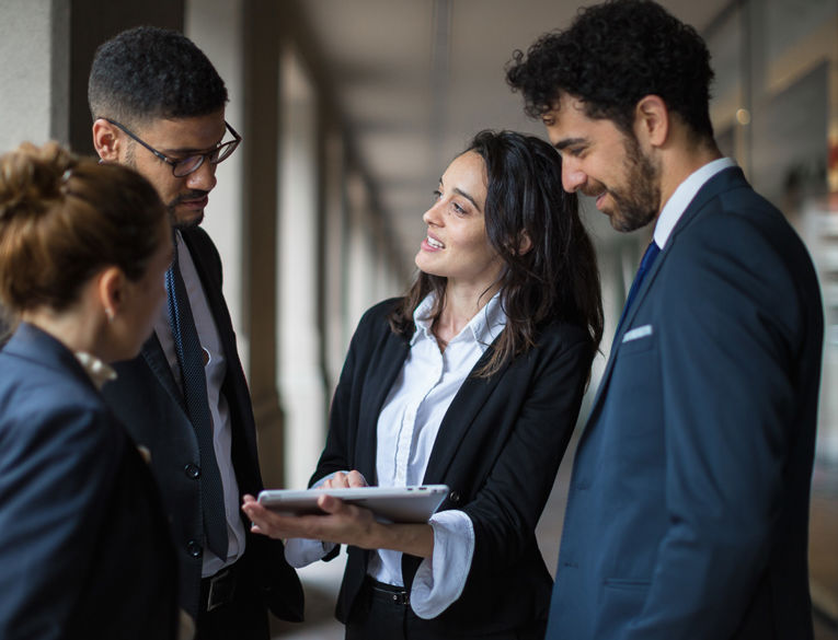 A manager presents data on a tablet to her team in suits – enabling efficient planning and time tracking in professional workflows.