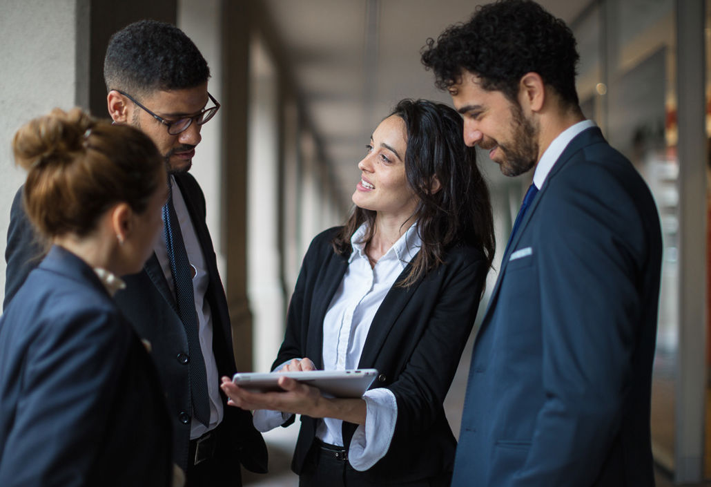 A manager presents data on a tablet to her team in suits – enabling efficient planning and time tracking in professional workflows.