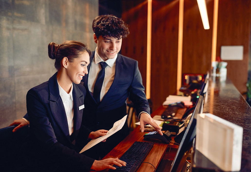 Two hotel receptionists collaborating at a computer, representing teamwork, efficient scheduling, and workforce management