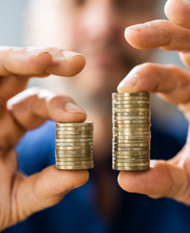 A person holds two stacks of coins of different heights, illustrating the pay differences addressed by the EU Pay Transparency Directive.