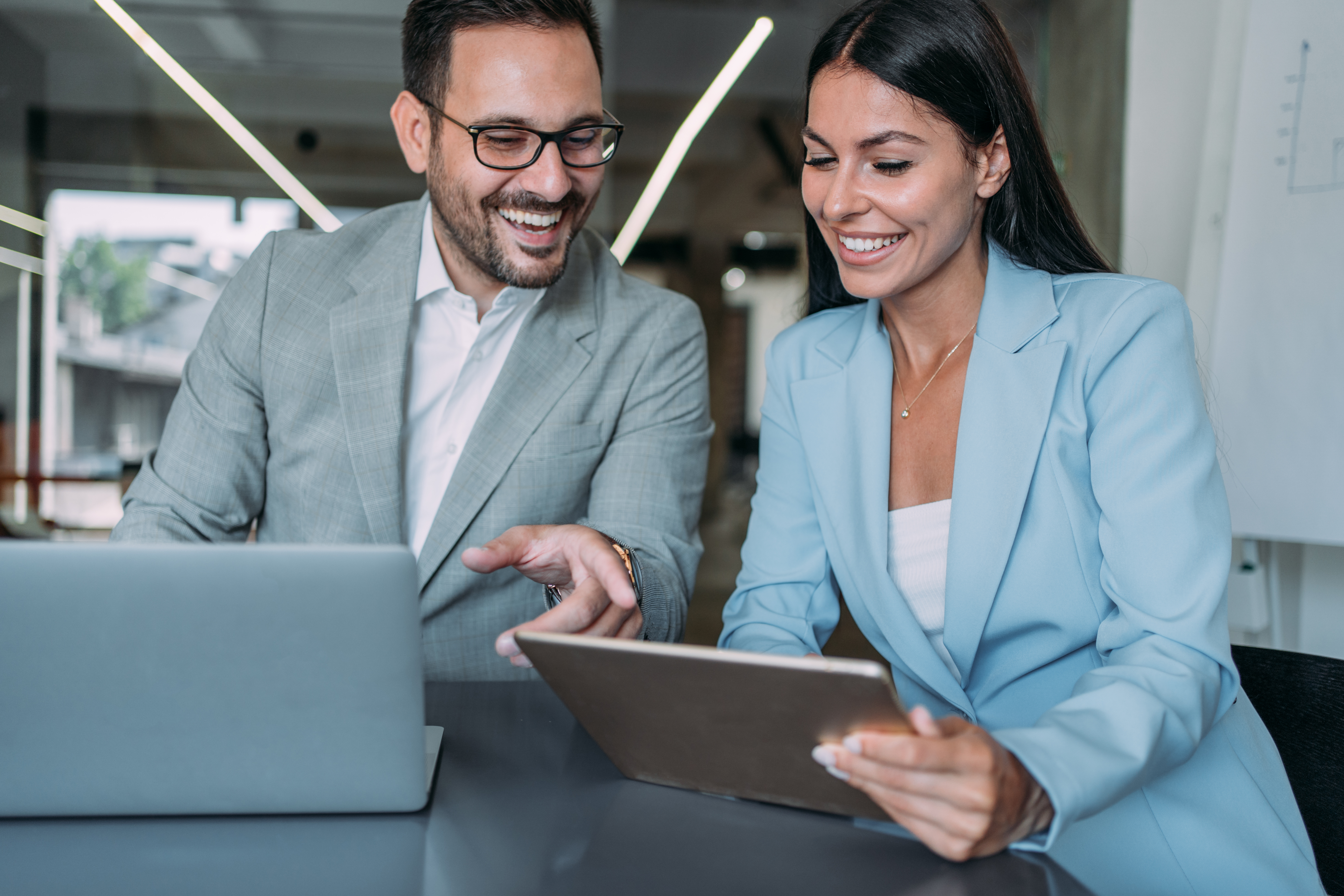 Woman amd man working on a laptop in an office as part of work on pay transparency and reviewing pay data.