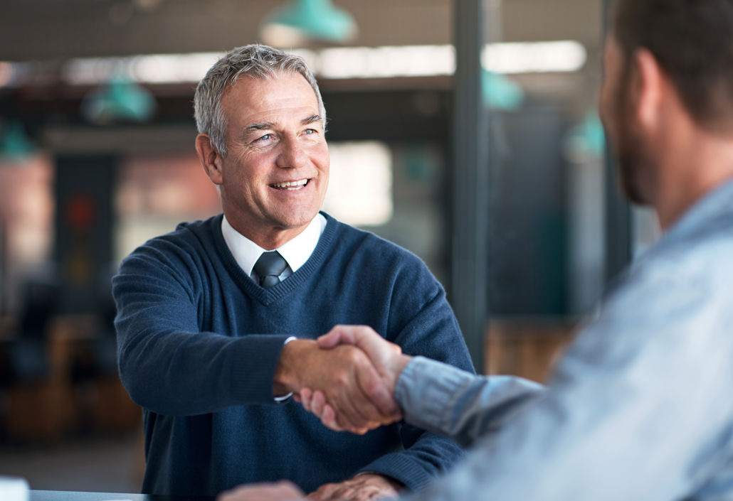 Smiling professional shaking hands after a successful salary negotiation, symbolising fair compensation agreements and positive employer-employee dialogue.