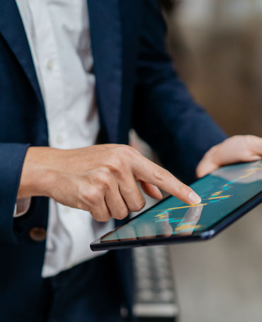 Business professional using a tablet to review data-driven insights, illustrating how to create effective work schedules with real-time planning tools.