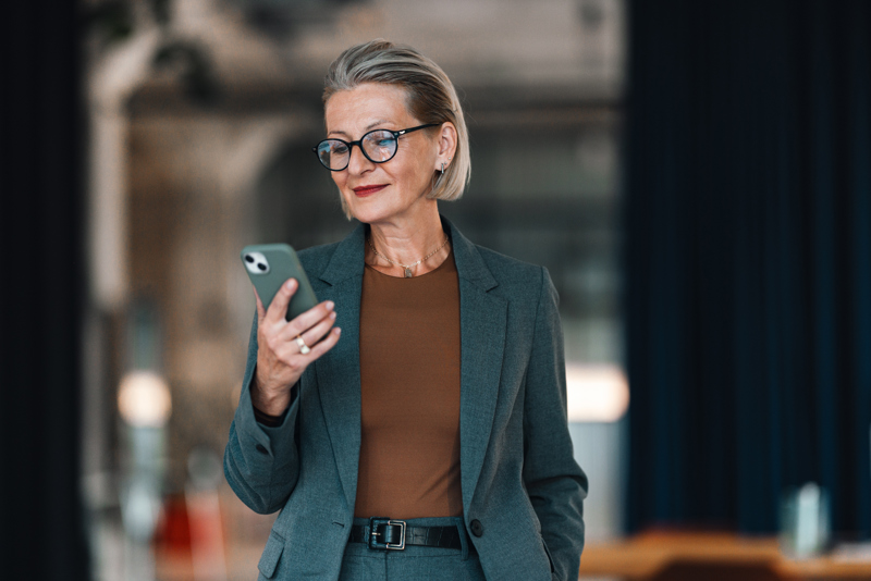 Manager checking staff schedules and time tracking on a smartphone through an AI-driven workforce management solution, providing an overview of employees and planning.