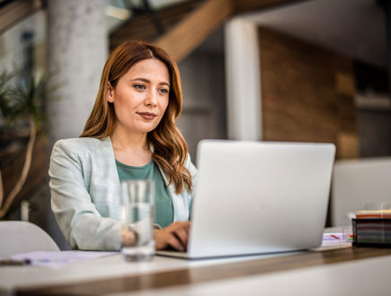 Manager using a digital workforce management system for shift scheduling and time tracking while working on a laptop.