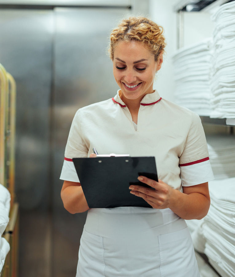 A hotel housekeeping supervisor inspecting fresh linens on a housekeeping cart to ensure high cleaning standards.
