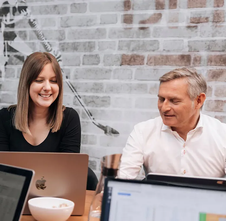 Software4You team members collaborating around laptops in a meeting, reviewing HR data and planning tools integrated with Timegrip for workforce optimisation.