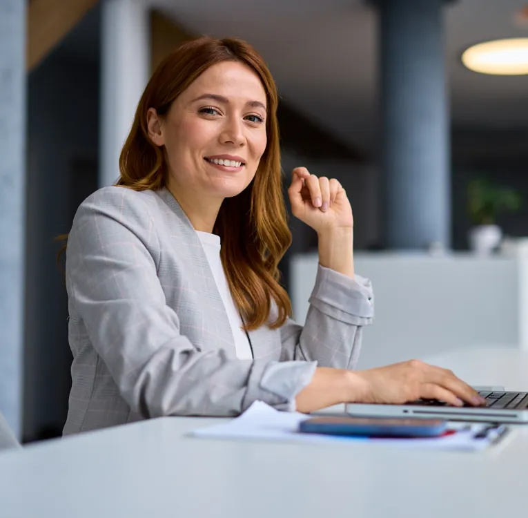 Confident businesswoman working on a laptop in a modern office, optimising workforce scheduling for better productivity.