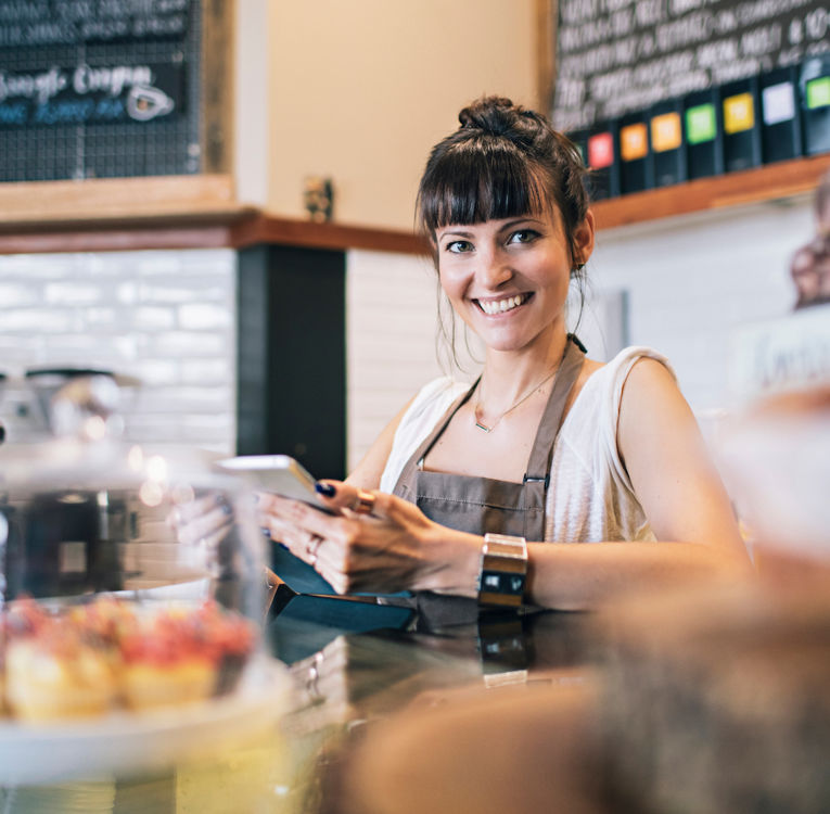 A cheerful café worker serving coffee and pastries, enhancing customer experience.