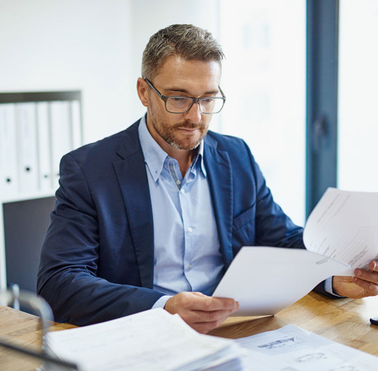Man in a suit reviewing documents at a desk, symbolizing professionalism and strategic workforce management and scheduling